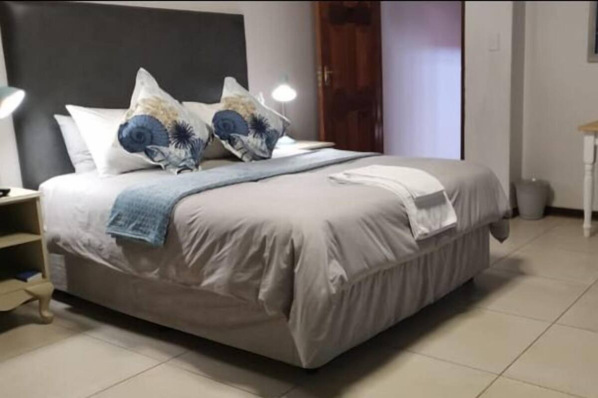 A neatly made bed with a beige comforter and blue and white patterned pillows.