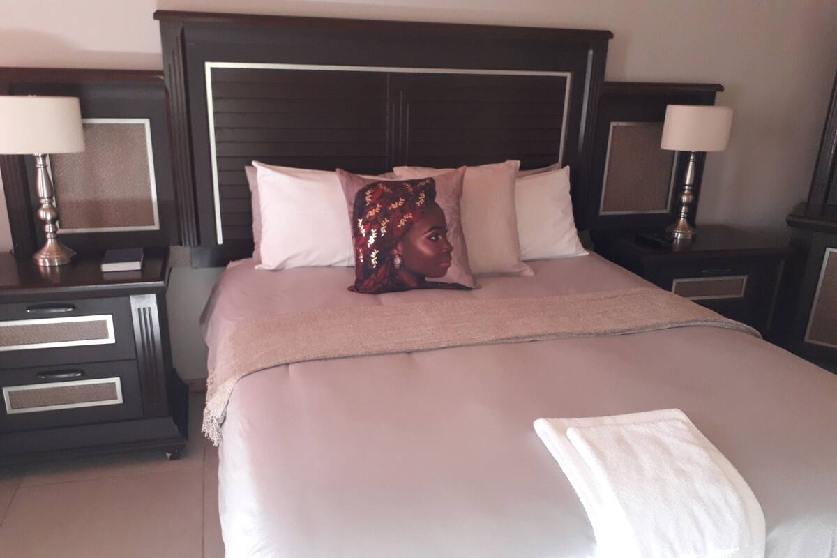 A neatly made bed with a headboard, two bedside tables with lamps, and a bedside drawer unit.