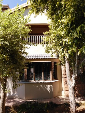 A house with a tiled roof, a window with a metal grille, and a brick wall. - Tuscany Boutique Hotel (Vryburg)