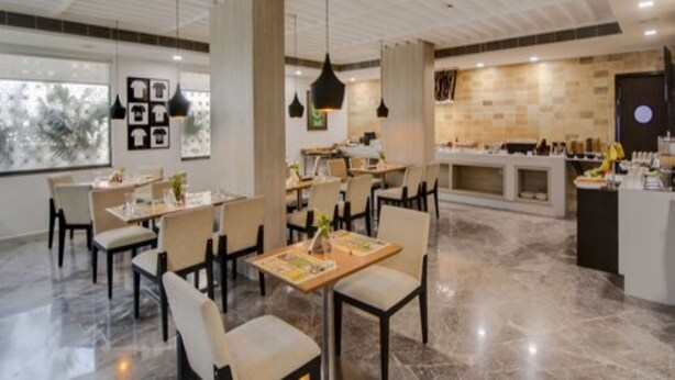 A modern restaurant with marble flooring, pendant lighting, and a central island. - Lemon Tree Hotel Banjara Hills (Hyderabad)
