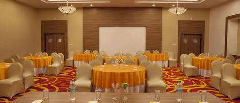 A conference room with round tables, chairs, and a large screen.