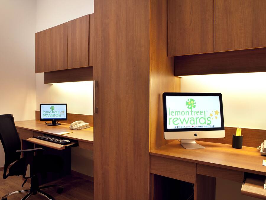A modern office space with two desktop computers, a black office chair, and wooden desks.