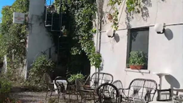 A courtyard with outdoor seating, potted plants, and a building with a white facade and satellite dishes. - Le Dieci Querce (Tortorella)