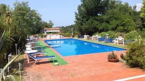 A rectangular swimming pool with a tiled deck, surrounded by greenery and a small pavilion. - Le Dieci Querce (Tortorella)