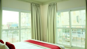 A hotel room with a bed, large windows, and curtains. - Al Nile Hotel (Salalah)