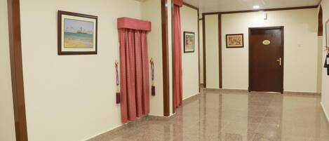 A hallway with a polished floor, framed pictures on the walls, and a door with a sign.
