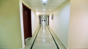 A long, narrow hallway with a tiled floor and a green stripe running down the center. - Al Nile Hotel (Salalah)