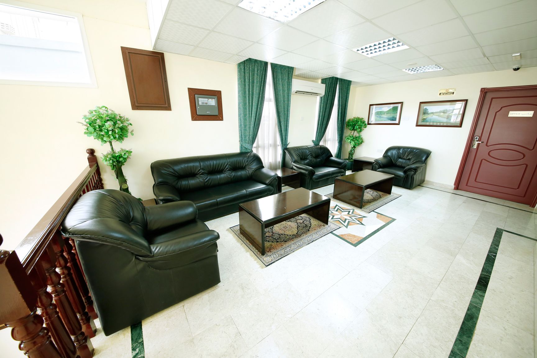 A spacious living area with a sofa set, coffee tables, and a red door.
