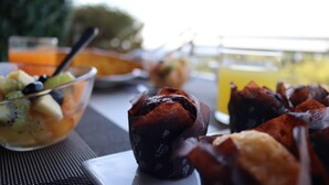 Una mesa con un frutero, un muffin y un vaso de jugo de naranja.