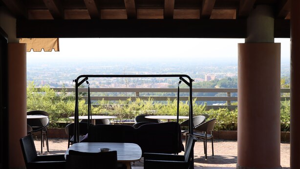 Un patio exterior con un columpio, mesas y sillas, con vistas a un paisaje pintoresco.