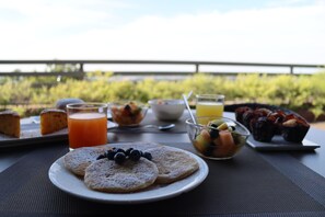 A breakfast table with pastries, fruit, and juice, overlooking a scenic view. - Albergo Alla Pineta (Montebelluna)
