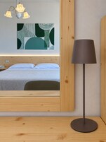 Un dormitorio moderno con cama, mesita de noche, lámpara y una obra de arte colgada en la pared.