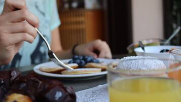 A dining table with a plate of food, a glass of juice, and a person eating.