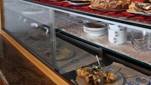 Un bufé con diferentes opciones de comida y una vitrina de vidrio.