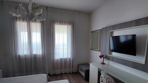 Habitación de hotel con una cama grande, un escritorio con televisión de pantalla plana y un candelabro.