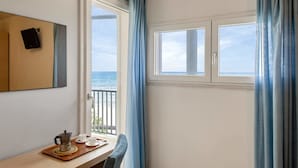 Une chambre avec vue sur la mer, une table avec une machine à café et des tasses, et un tableau accroché au mur.