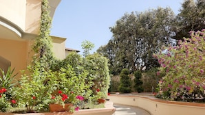Une cour aménagée avec un sentier sinueux, des plantes en pot et une variété d’arbres et d’arbustes.