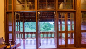 A wooden structure with large glass doors leading to an outdoor area with a wooden deck and a bench. - Bulaeinn Villas (Bago)