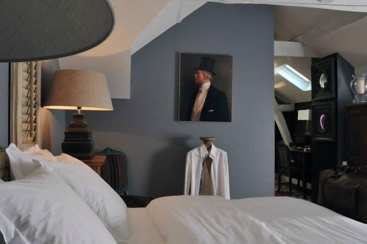 Ein Hotelzimmer mit einem Bett, einer Lampe, einem Kleiderhaken und einem Bild an der Wand.