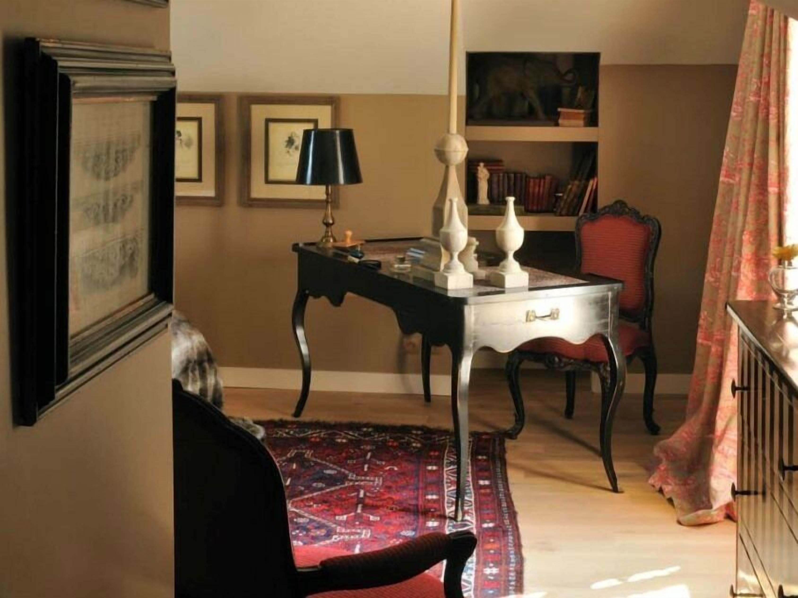 A room with a desk, chair, bookshelf, and a patterned rug.