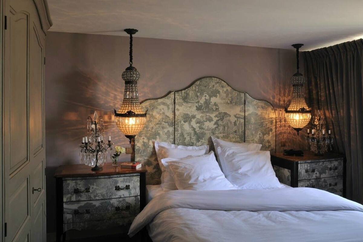Ein Schlafzimmer mit einem großen Bett, zwei Nachttischen mit verzierten Lampen und einem Kopfteil mit Blumenmuster.