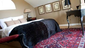A bedroom with a bed, a red patterned rug, a lamp, and framed pictures on the wall.