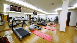 Ein Fitnessstudio mit Laufbändern, Crosstrainern und Trainingsmatten.