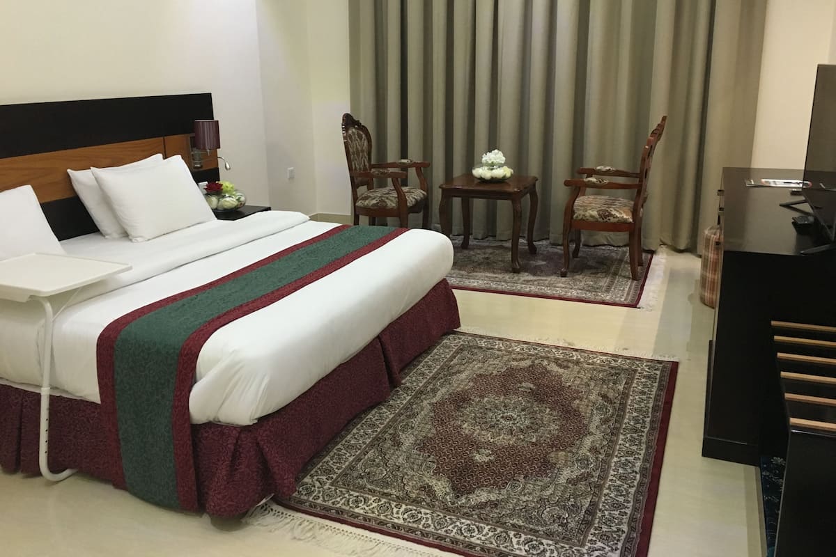 A hotel room with a bed, a desk, a chair, a TV, and a window with curtains.