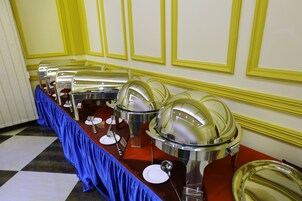 Montaje tipo bufé con varias estaciones de servicio, cada una con un recipiente cubierto y un plato.