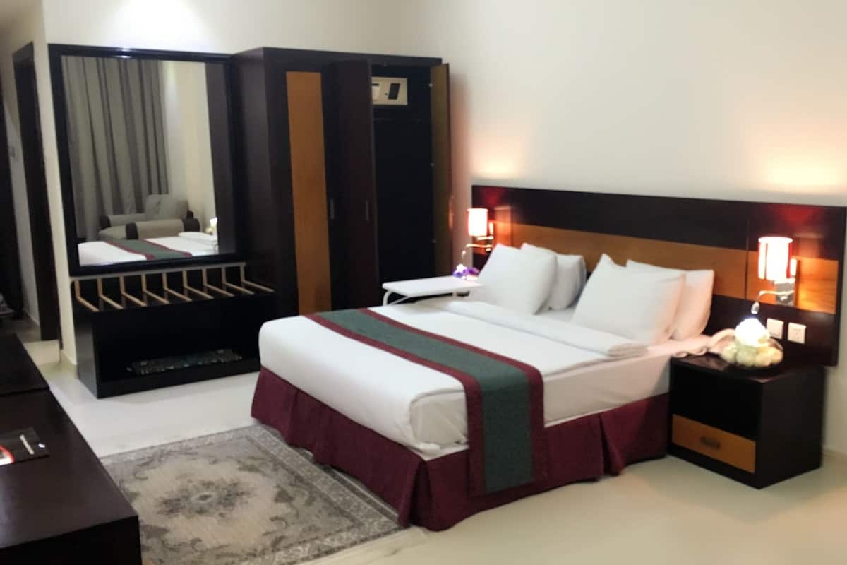 A hotel room with a bed, bedside tables, a wardrobe, and a mirror.