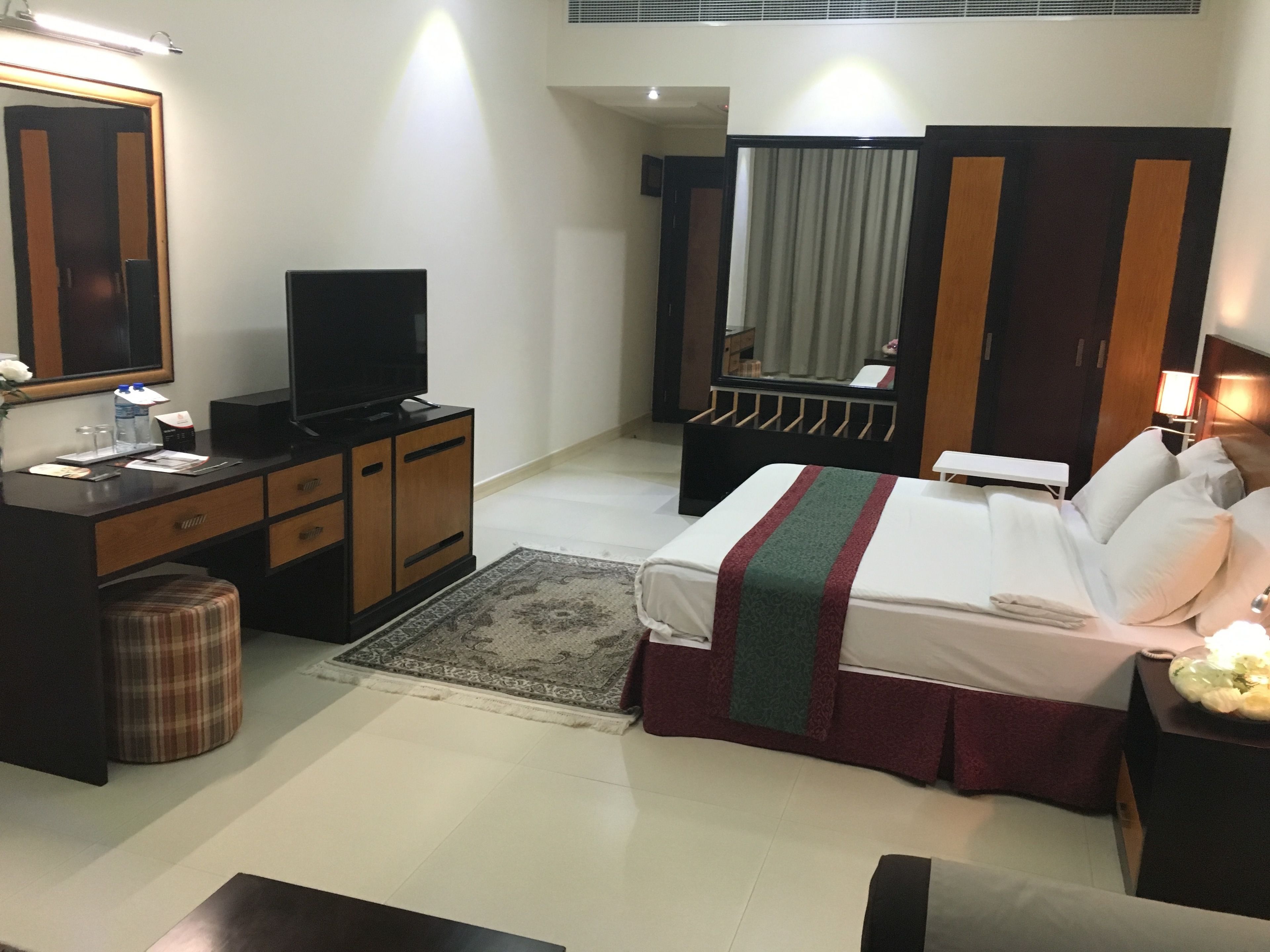Une chambre d’hôtel comprenant un lit, un bureau avec une télévision, une armoire et un miroir.