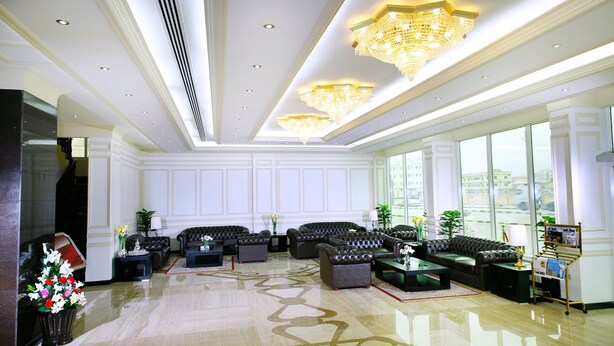 Eine geräumige Lobby mit großzügiger Sitzecke, einer Rezeption und einem Chandelier.