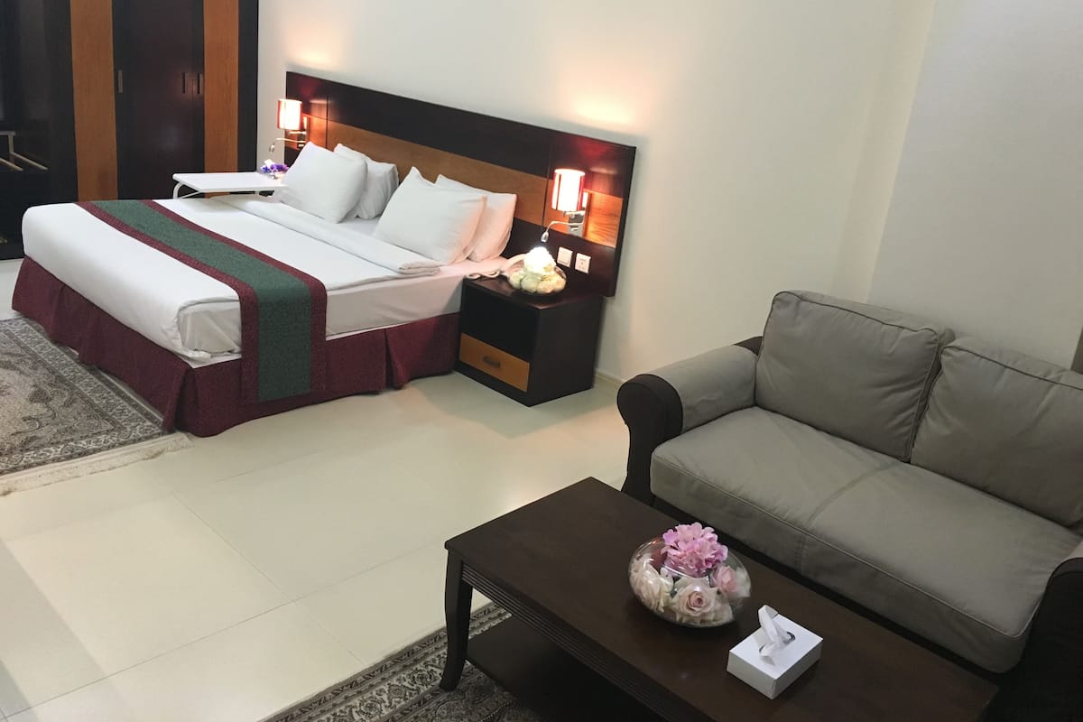 A hotel room with a bed, a nightstand, a bedside table, a sofa, and a coffee table.
