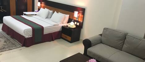 Una habitación de hotel con cama, mesita de noche, sofá y mesa de centro.