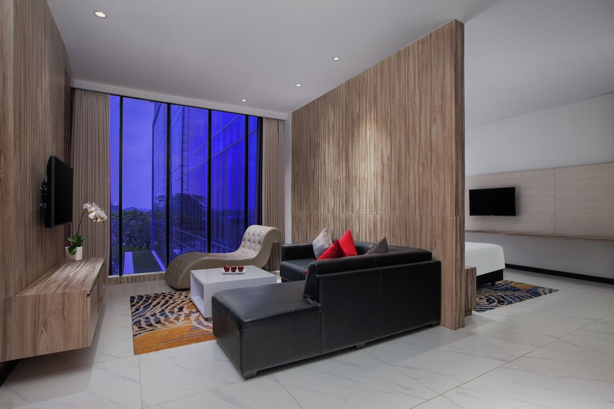 Una sala moderna con sofá, sillón y televisor de pantalla plana en la pared.