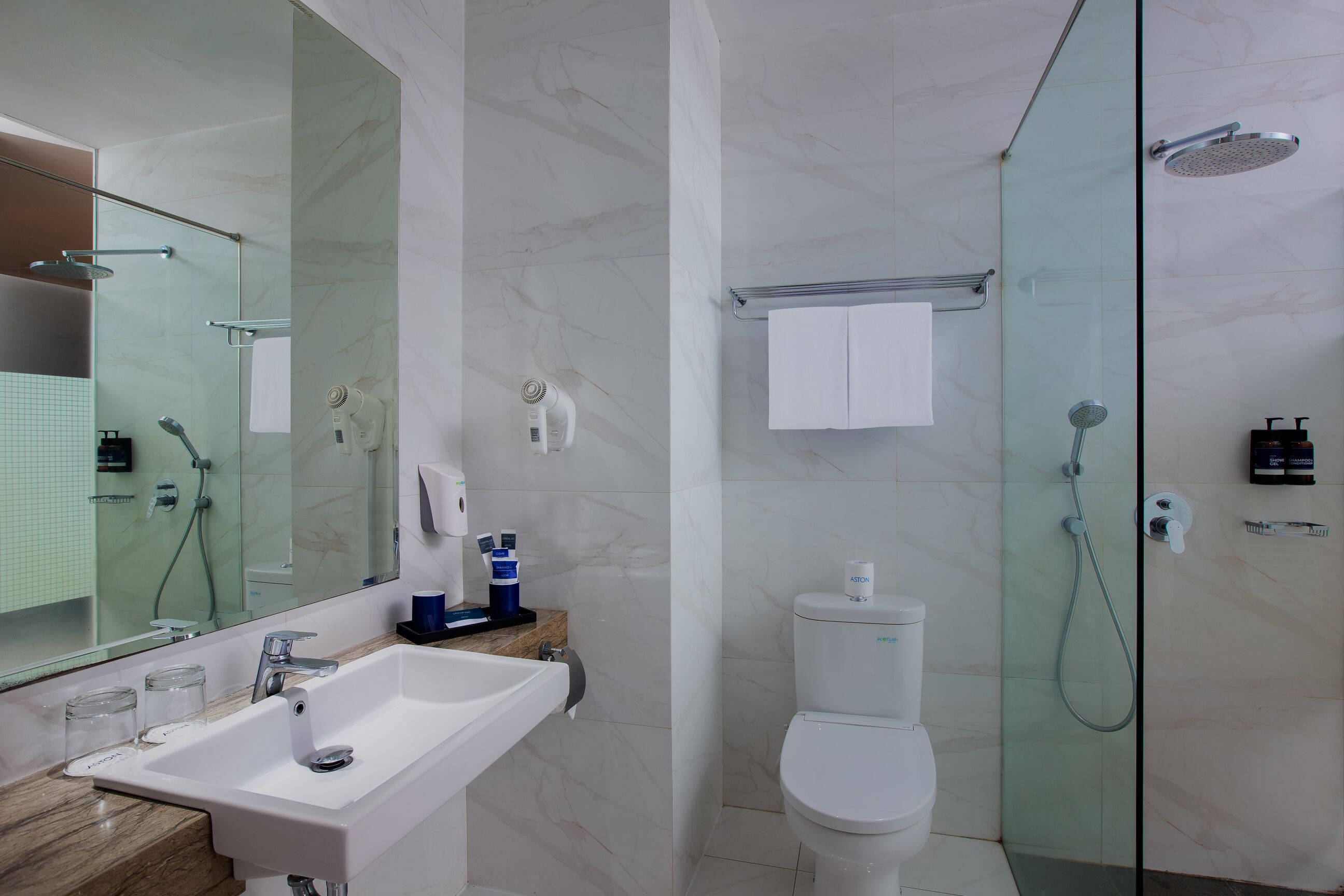 Un baño moderno con cabina de ducha de vidrio, lavamanos blanco y retrete.