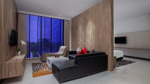 A modern living room with a sofa, armchair, and a flat-screen TV mounted on the wall. - Aston Inn Tasikmalaya (Tasikmalaya)