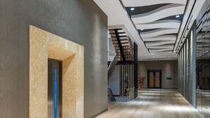 A modern hotel lobby with a wooden floor, a staircase, and a wall-mounted sign. - Aston Inn Tasikmalaya (Tasikmalaya)