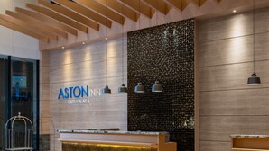 A reception desk with a modern design, a wooden ceiling, and a wall with a textured pattern. - Aston Inn Tasikmalaya (Tasikmalaya)