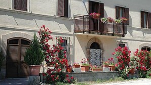 A building with a balcony, potted plants, and a patterned door. - Agriturismo Monti Sibillini Camperato (Preci)