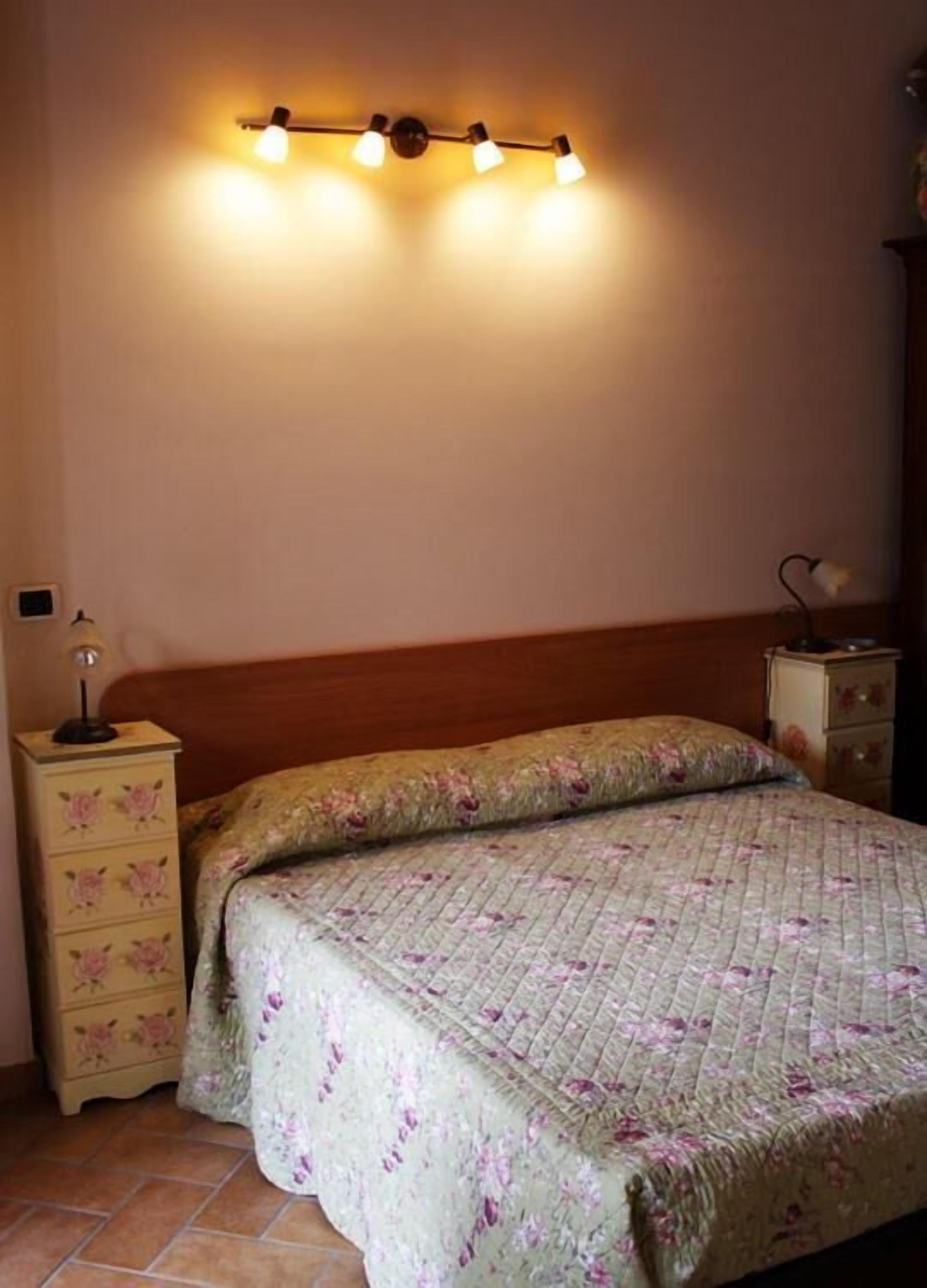 Un dormitorio con cama, mesita de noche y lámpara de pared.