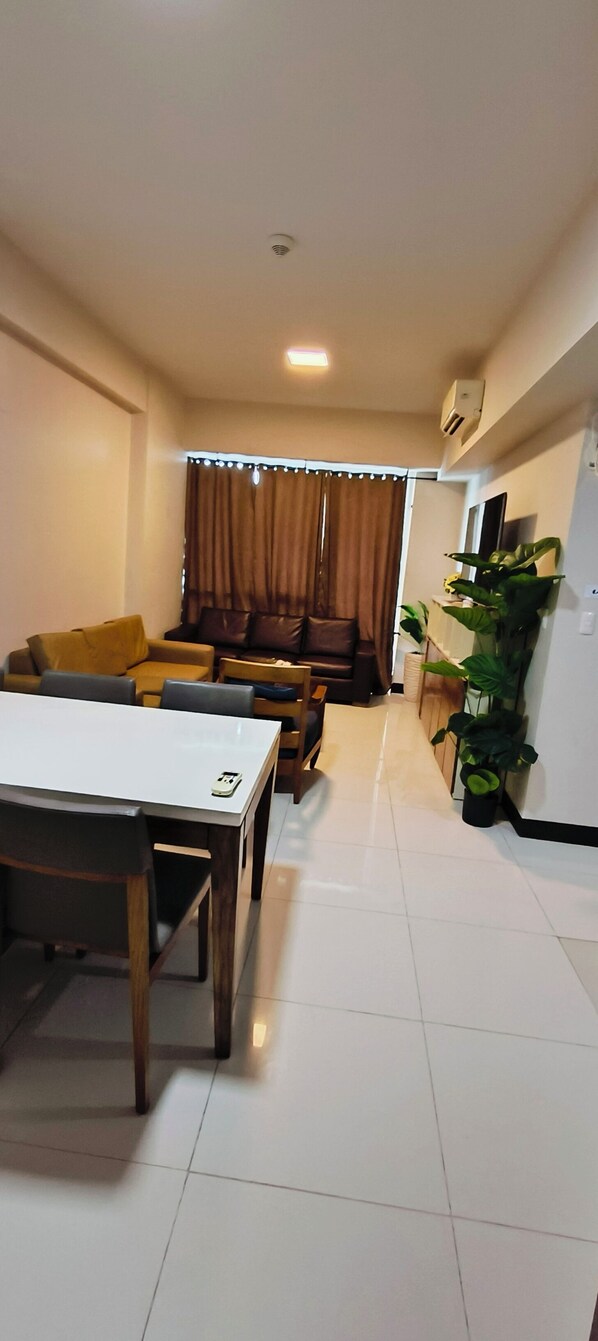 A living room with a dining table, sofas, and a TV. - My Suits at Mactan Newton (Lapu-Lapu)