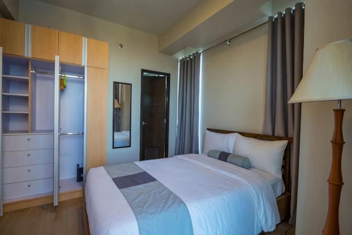 A bedroom with a bed, a wardrobe, a mirror, and a lamp.
