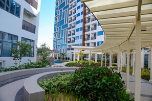 A modern building with a covered outdoor area, a pool, and a landscaped garden.
