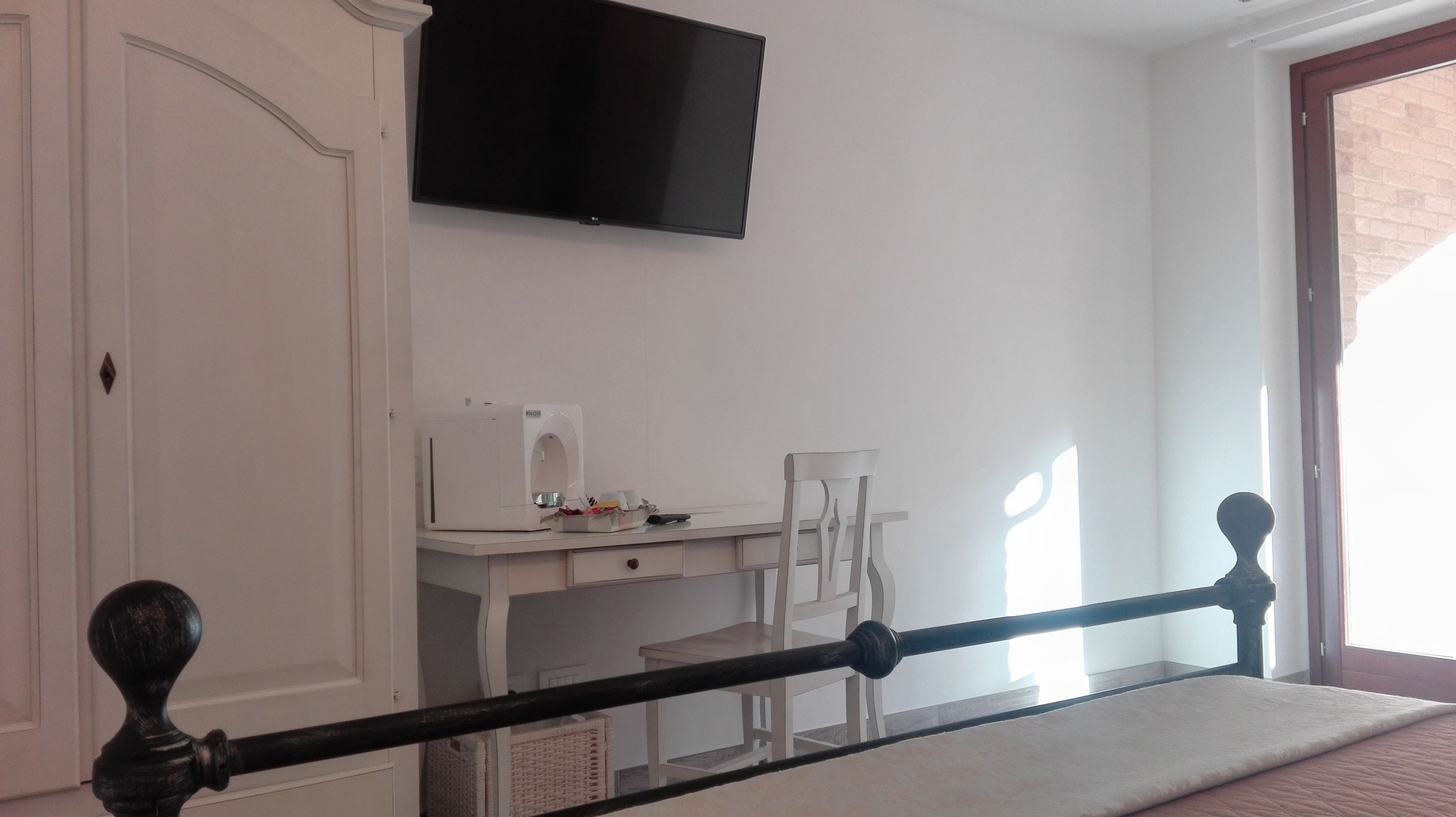 A room with a bed, a desk with a chair, a flat-screen TV, and a window.