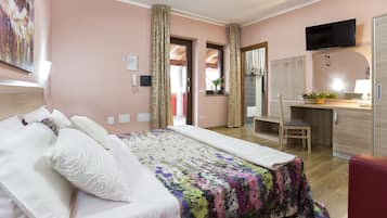 A hotel room with a bed, a desk, a chair, a TV, and a bathroom visible through an open door.