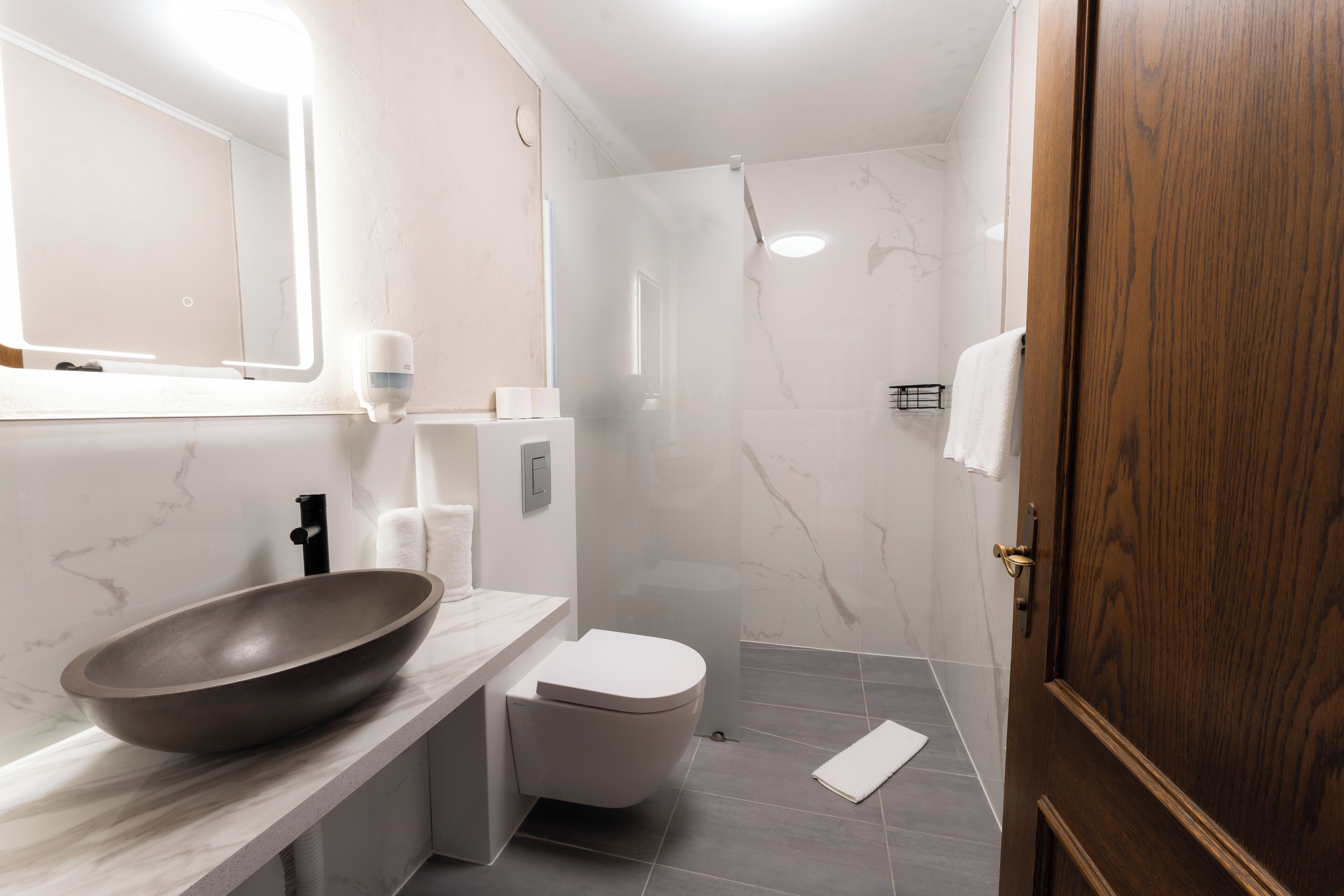 A modern bathroom with a large vessel sink, a toilet, and a shower area.