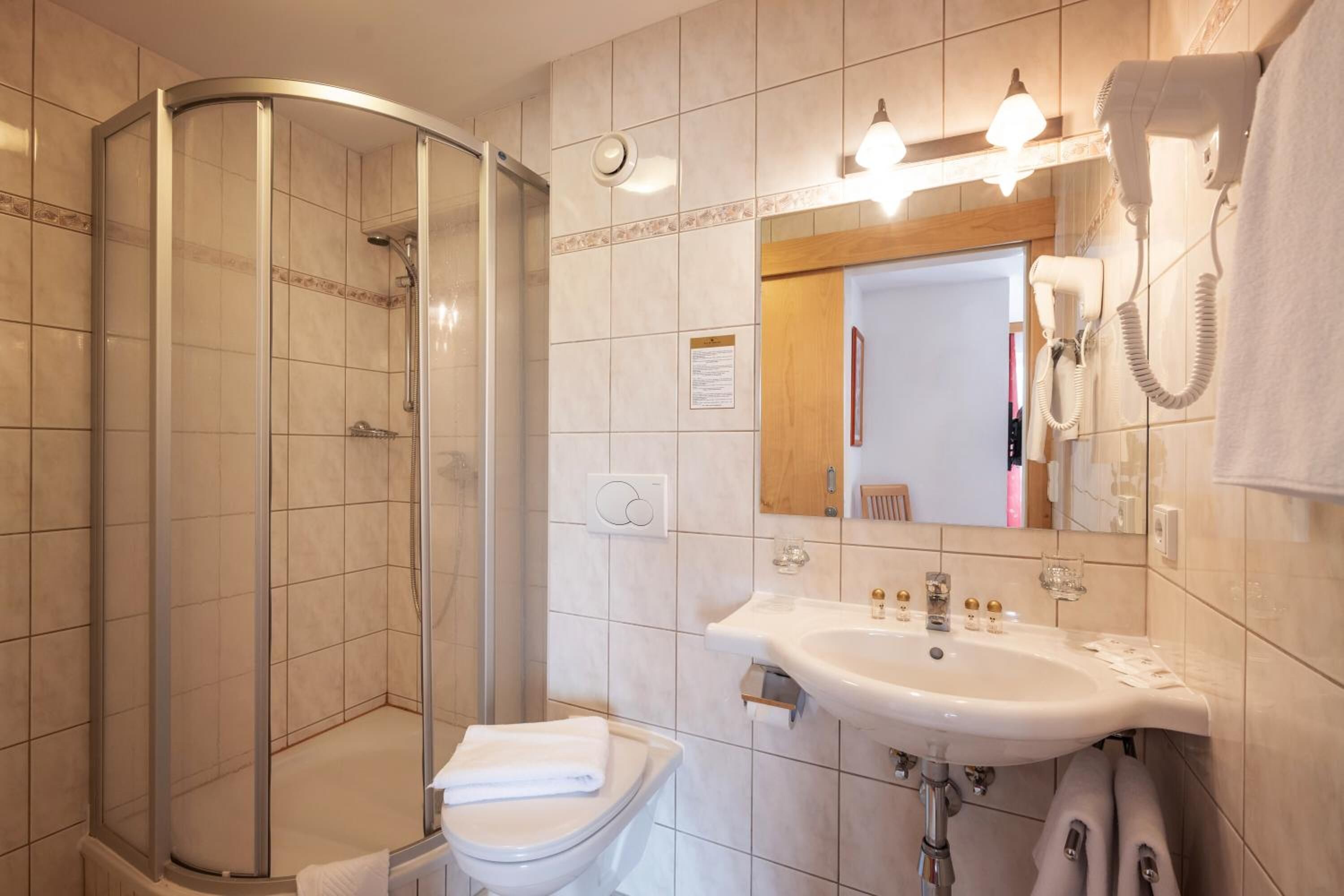 Une salle de bain moderne avec une douche à parois de verre, un lavabo avec un miroir et des toilettes.