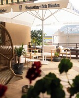Terraço no telhado com área de estar ao ar livre, plantas em vasos e vista da cidade.