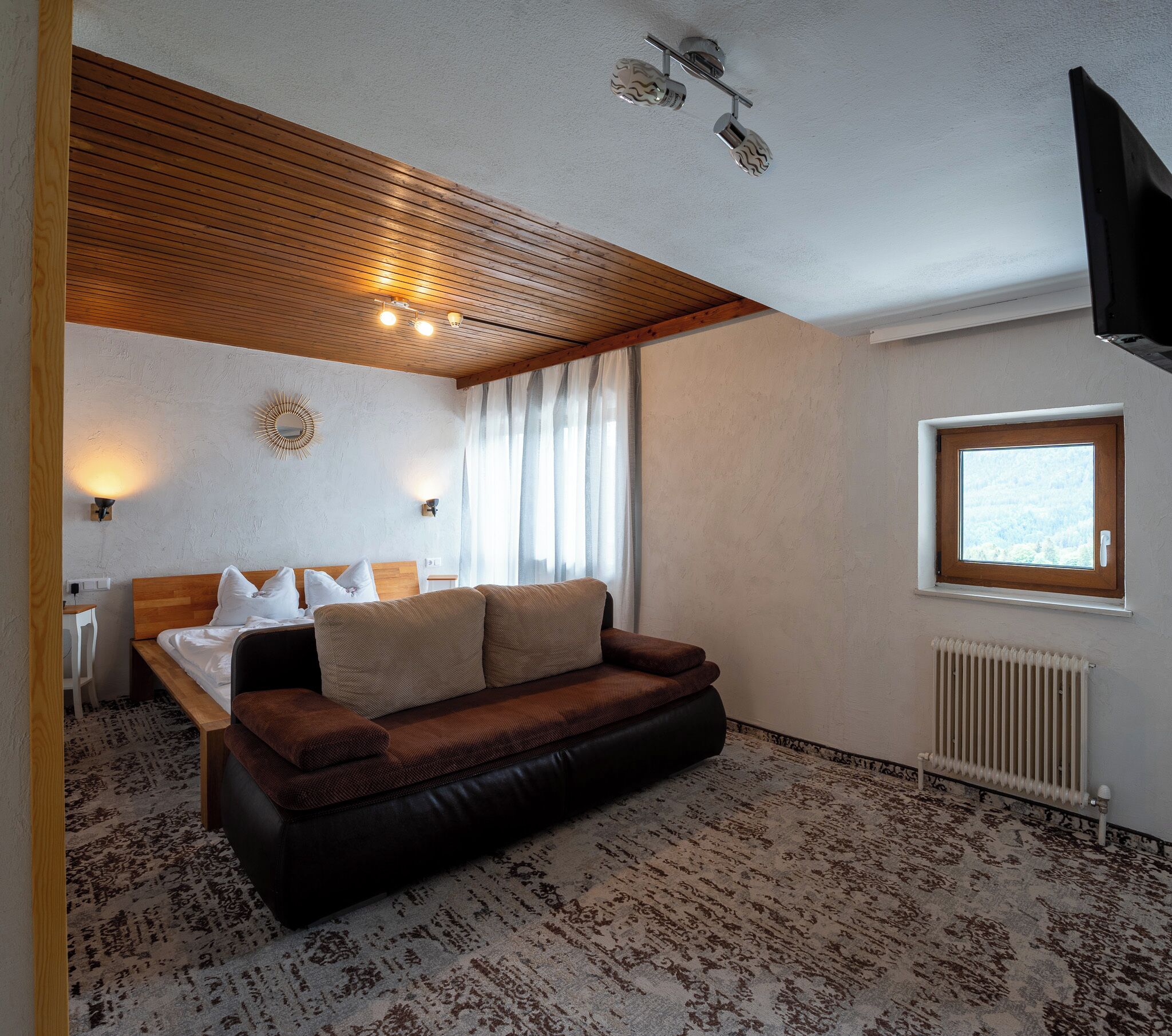 Una habitación con una cama, un sofá, un escritorio y una ventana.